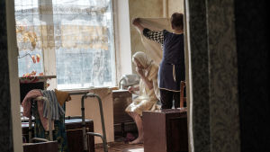 På åldringshemmet i Luhansk bor femtio åldringar. Deras pensionspengar finansierar hemmet så gott det går - men det räcker inte. En sköterska byter lakan åt en åldring i åldringshemmet i Ukraina.