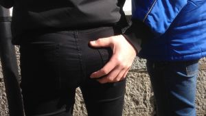 Pojke sätter sin hand på en flickas rumpa