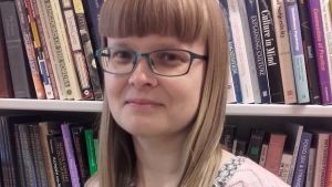 Sofia Sjö forskar i religionsvetenskap vid Åbo Akademi. Sofia Sjö poserar framför en bokhylla