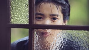 Jungfrun i fönstret. Tjänsteflickan Sook-Hee (Tae-ri Kim) vet inte vad hon skall tycka om allt hon får se i sitt nya hem. Tjänsteflickan Sok-Hee (Tae-ri Kim) kikar in genom ett fönster.