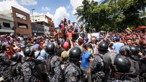 Kravallpolis i förgrunden då regeringsanhängare och -motståndare hotar att drabba samman i Caracas under den informella folkomröstningen. Kravallpolis i förgrunden då regeringsanhängare och -motståndare hotar att drabba samman i Caracas under den informella folomröstningen 16.7.2017