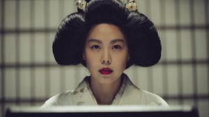 Ingen vanlig sagotant. De ord som trillar över Lady Hidekos (Min-hee Kim) läppar sätter kroppar i brand. Lady Hideko i närbild när hon hårt sminkad läser.