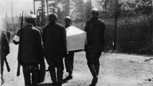En död fånge förs bort av andra fångar. Fångar bär vit likkista på Sveaborg 1918