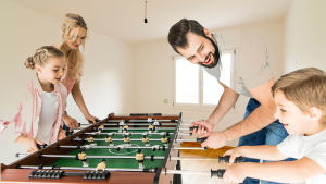 Drömlik bild med familj som spelar foosball i lägenhet utan andra möbler
