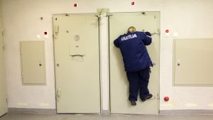 Kikhålen i häktet är anpassat för normalbygda män - inte för korta kvinnor. Men Ulpu Keränen har utvecklat sin egen teknik för att kunna se in i cellen. Väktare Ulpu Keränen kikar in i en cell.