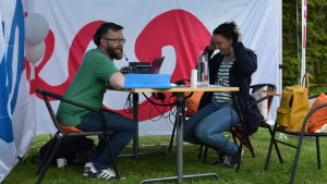 Jocke Lax och Anne Teir-Siltanen från Yle Vega sände från trädgårdskvällen 2017. Man och kvinna sitter vid ett bord och sänder radio utomhus.
