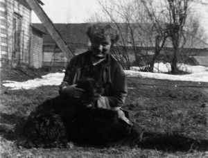 Edith Södergran istuu pihassa koira sylissään