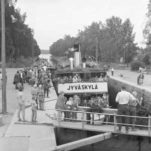 S/S Jyväskylä matkustajineen Vääksyn kanavassa 1950-luvun lopussa. Mustavalkoinen kuva: Höyrylaiva S/S Jyväskylä Vääksyn kanavan suluilla ihmisten saartamana.