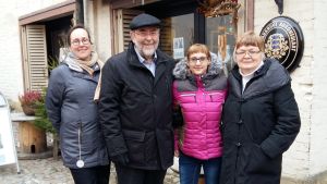 Estlandsengagerade Kirsi Äyräs, Asko Puikkonen, Aljona Virolainen och Solveig Sjöberg-Pietarinen. två glada män och kvinnor står framför ett fönster och en skylt på stenig gårdsplan