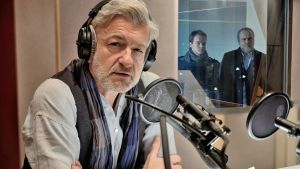 Ketun uuden jaksot alkavat. Mies istuu radiostudiossa mikrofonin edessä. Takana ikkunasta katsoo sisään kaksi miestä.