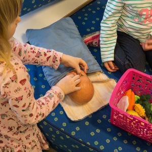 Dagisbarn leker med docka