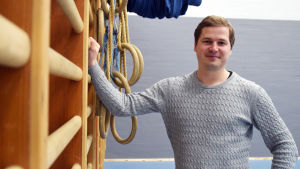 Gymnastikläraren Mats Engblom skrev sin pro gradu-avhandling om samgymnastik. Mats Engblom står vid några ribbstolar i en gymnastiksal.