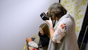 Mamma Tiina Suikkanen får hålla sin nyfödda medan Marit Björkbacka fotograferar. Kvinna fotograferar bebis