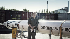 Peter Madsen drömmer om att nå rymden i en egenhändigt byggd raket. Peter Madsen står framför raketen och blickar mot himlen.