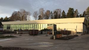 Renoveringen av simhallen i Hagalund blir inte klar i år. Simhallen i Hagalund med stängsel framför.