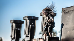 Bassisten Jonathan Olsson från bandet Pain står och headbangar på scenen.