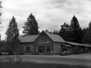 En affär i närheten av Pulsa station i slutet av 1980-talet. Mustavalkoisessa arkistokuvassa harjakattoinen vanha myymälä, teksti Pulsan puoti