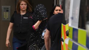 En kvinna förs ut ur ett bostadshus av polis i Barking. En kvinna förs ut ur ett bostadshus av polis i Barking.
