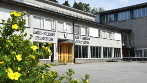 Jan-Erik Till började jobba i Karis hösten 1990. Före det jobbade han som lärare i Virkby. Bild på ett gymnasium med blommor i förgrunden