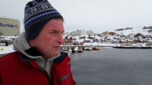 Yrkesfiskaren Jakob West tränar 4-5 gånger per år i mycket svåra förhållanden, för att vara beredd om oljeolyckan är framme. Jakob i röd jacka, i profil, blickar ut mot havet, en oljebehållare och små hus i bakgrunden.
