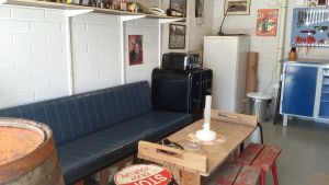 Blå lädersoffa, träbord och roliga pallar bjuder in till Sture Nylunds garage. En blå lädersoffa bjuder in gäster till Sture Nylunds garage