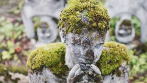 Veijo Rönkkönen ville att tidens tand skulle gnaga på hans kreationer - därför får mossan breda ut sig över statyerna. En del reparationer har parkinspektorerna ändå utfört. Mossklädd betongstaty föreställande person som lutar ansiktet i knäppta händer.