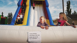 Här finns något att göra för hela familjen. Två flickor vid en hoppborg och rutschkana.