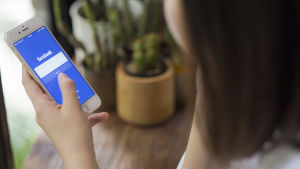 webbplattformerna måste ta ansvar för kommentarerna, anser Ribbing. En kvinna håller en smarttelefon i handen med Facebook öppen.