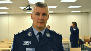 Risto Lammi. En bild av polischef risto lammi. I bakgrunden i konferensrummet står andra poliser men de är ur fokus.
