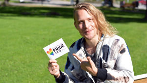 Simon Zion gör en akustisk spelning på Raseborg Pride. Simon Zion med ett kort i handen där det står Raseborg Pride.