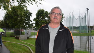 Ronnie Westerlund på gatuavdelningen i Raseborg försäkrar att översvämningen vid centralidrottsplanen åtgärdas så snabbt som möjligt. Arbetsledare Ronnie Westerlund med den översvämmade idrottsplanen i bakgrunden.