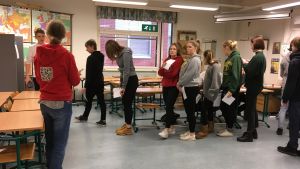 Elever köar till valbåset. Lärare Sonja Kotakallio övervakar. Elever köar till valbåset.