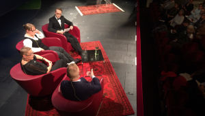 Henrik Meinander, Suvi Ahola och Anu Lahtinen med Axel Åhman funderar bland annat på vilka finländska storkvinnor som vore värda en staty. Historikerna Henrik Meinander och Anu Lahtinen och journalisten Suvi Ahola i paneldebatten om storkvinnor vid Föredragsmaraton i Helsingfors den 8 september 2017. Debatten leddes av Axel Åman.