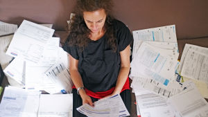 Alla konsumenter kan inte ta till sig all information, och då det blir för mycket att ta in så leder det till att konsumenten inte kan fatta rationella beslut. Kvinna sitter i ett hav av räkningar.