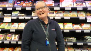 Carolina Kallström plockar upp varor och svarar på kunders frågor om mat. Carolina Kallström står framför en butikshylla med färdigmat.