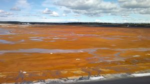Gruvan i Sotkamo har tampats med stora problem. Ett fält med orangefärgat slem och jord på marken i Sotkamo.