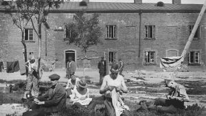 Fångar som reparerar sina kläder på gården. Fångar på Sveaborg 1918, syr kläder på gården