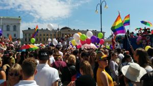 Prideparaden i Helsingfors sommaren 2016. Människor med ballonger och regnbågsflaggor på Senatstorget.