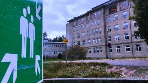 För ett par veckor sedan var huvudbyggnaden fortfarande tyst och öde i Mjölbolsta. En stor gammal stenbyggnad i flera våningar, grå. TIll vänster en grön skylt med två vita mänskofigurer i mitten och pilar runt omkring som visar att man vid nödfall ska samlas på den här platsen.