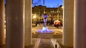 Ett ny staty i centrum av Skopje, Makedonien, fotad bakifrån och med en demonstration i bakgrunden.