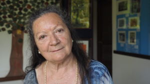 Elsa López Porträtt av poeten Elsa Lopez som ler i kameran med pärlhalsband runt nacken