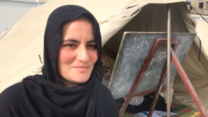 Vi behöver skollokaler, utrustning och flera lärare för att kunna ta hand om alla barnen, säger läraren Bibi Rahellah som arbetat här i sju år. En kvinnlig afghansk lärare i svart huvudduk utanför en tältskola