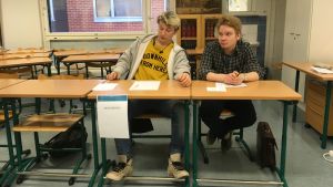 Fredrik Präst och Verner Etola är valfunktionärer i ungdomsvalet i Kyrkslätts gymnasium. Två personer sitter vid ett bord.