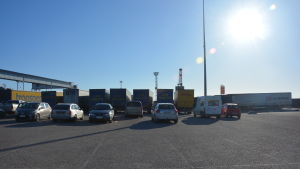 Långtradarna står uppradade vid Smörmagasinet i Hangö. En bild på nio långtradare som står uppradade på en parkering. Bilden är tagen motljus och himlen är blå.