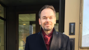 Folktingssekreteraren Markus Österlund vill att programmet under Svenska dagen klart skiljer sig från självständighetsdagens högtidligheter Man vid ingång till kontorshus i Helsingfors