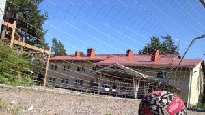Kirkonkylän koulu i Pojo är en aktiv föregångare i Västnyland. En boll på en sandplan. I bakgrunden ett fotbollsmål och en gul skolbyggnad.