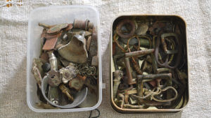 Det här ska bli smycken. Två lådor fyllda med olika metallföremål, till exempel spännen från bälten