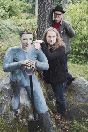 Kimmo Heikkilä och Atte Paju tillsammans med Veijo Rönkkönen. Två män och en staty som håller i en spade.