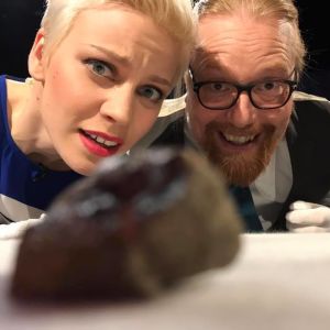 Etualalla Mars-meteoriitti, taustalla Prisma Studion juontaja Reetta Rönkä ja teollisuusmatemaatikko Samuli Siltanen. Prisma Studion juontaja Reetta Rönkä ja teollisuusmatemaatikko Samuli Siltanen katsovat Mars-meteoriittia