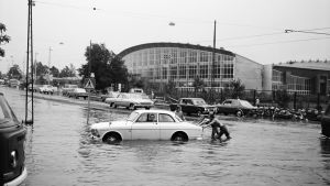 Nordenskiöldinkadulla tulvi v. 1972 Veteen juuttunutta autoa työnnetään tulvivalla Nordenskiöldinkadulla